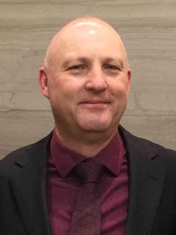 Headshot of Kanata Business Connections member Jeff Edwards wearing a burgundy collared shirt, burgundy tie, and black blazer