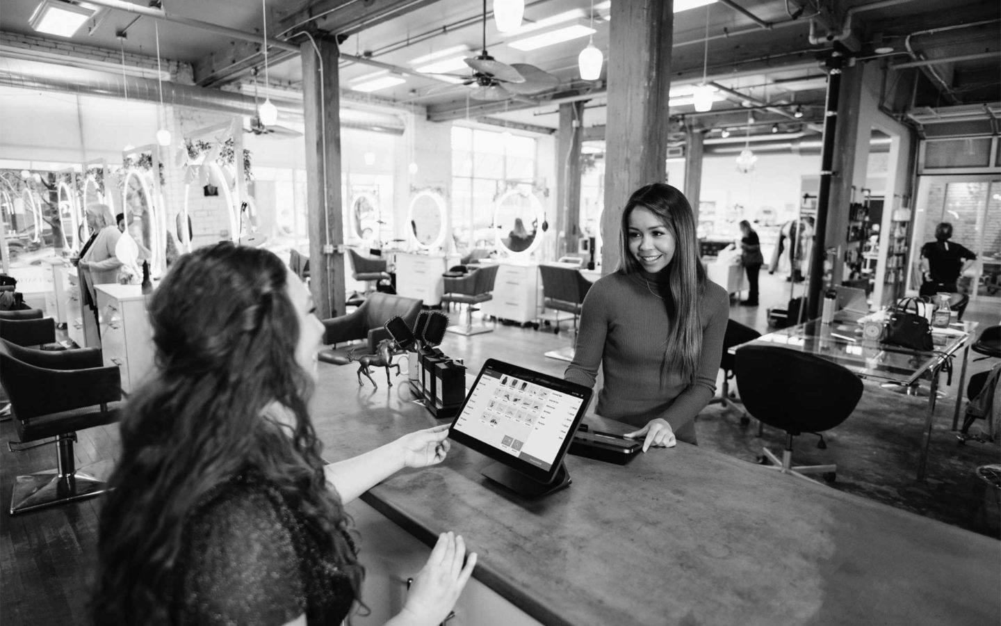 A young woman makes an appointment with the receptionist at a modern-looking beauty salon